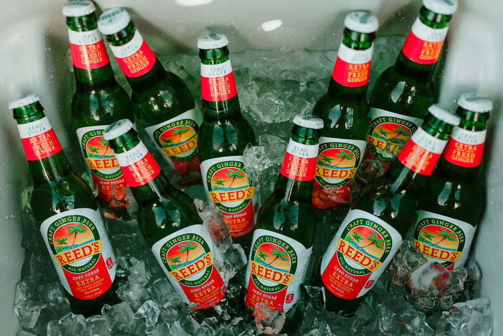 Glass bottles of Reed's Zero Sugar Extra Ginger Beer floating in ice.