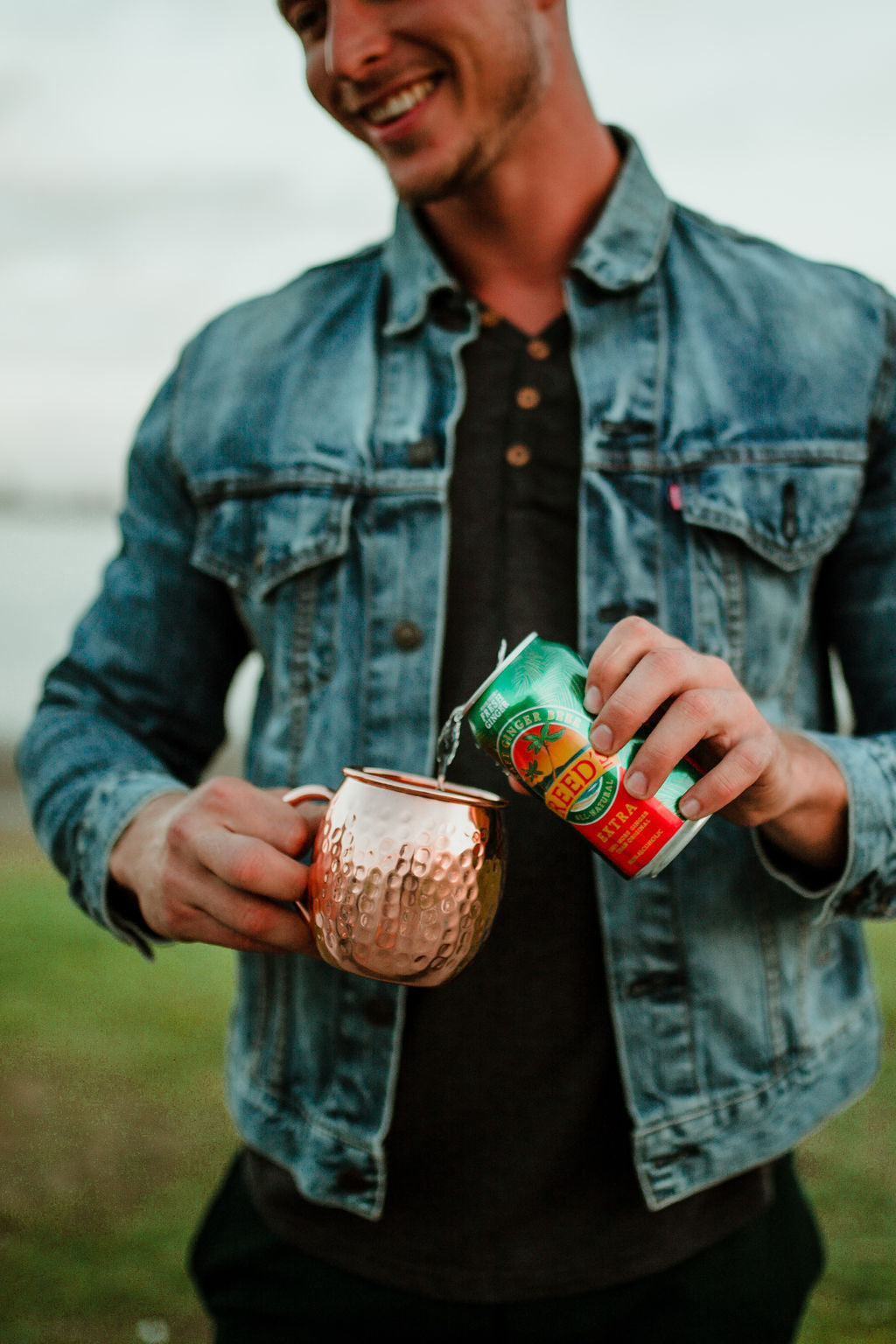 A man pouring a can of Reed's Extra Ginger Beer in a copper mug.